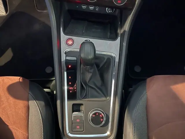 Vue plongeante sur la console centrale noire avec levier de vitesse automatique et sièges marron et noir du SEAT Ateca blanc.