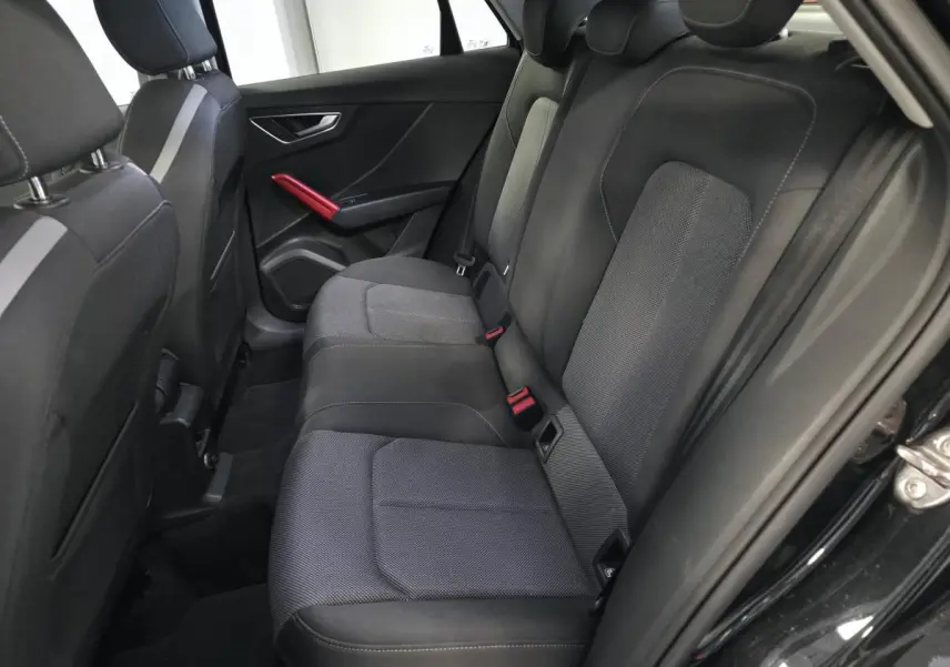 Vue intérieure arrière droite de l'Audi Q2 1.4 TFSI Sport 2017 avec sellerie noire et applications décoratives rouges.