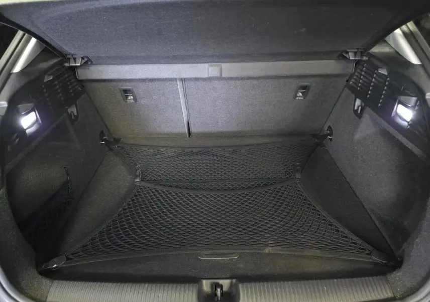 Coffre ouvert d'un Audi Q2 noir, montrant un filet de rangement et un intérieur entièrement noir avec éclairage latéral.