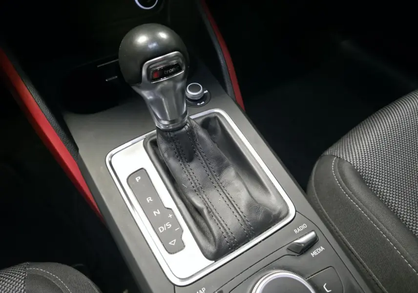 Le levier de vitesses automatique S tronic de l'Audi Q2 1.4 TFSI Sport avec garnitures intérieures rouges visibles.