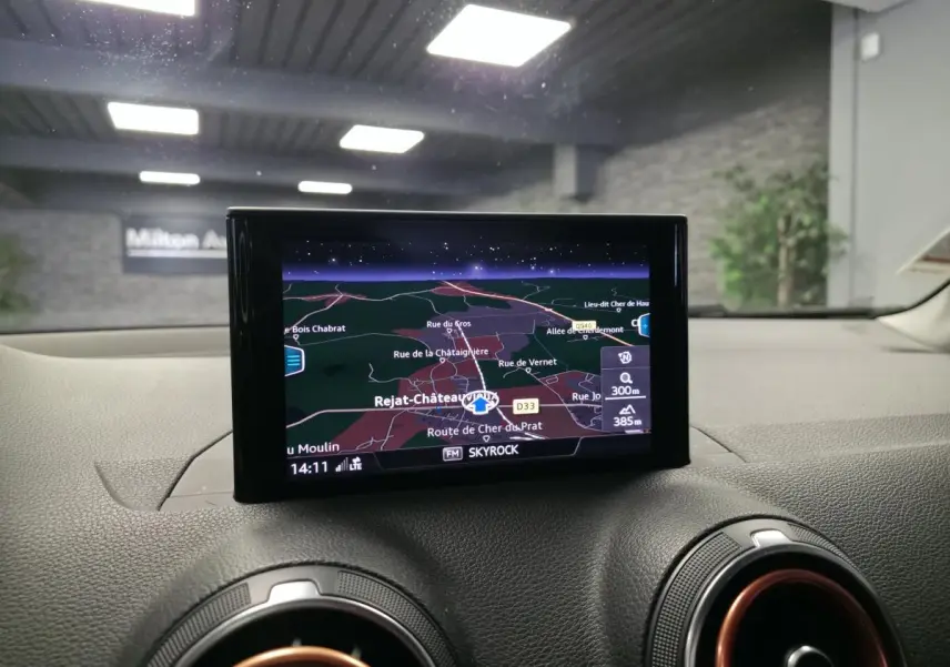 Écran de navigation MMI central dans l'habitacle d'Audi Q2 noir, avec détails de carte et ventilation rouge.