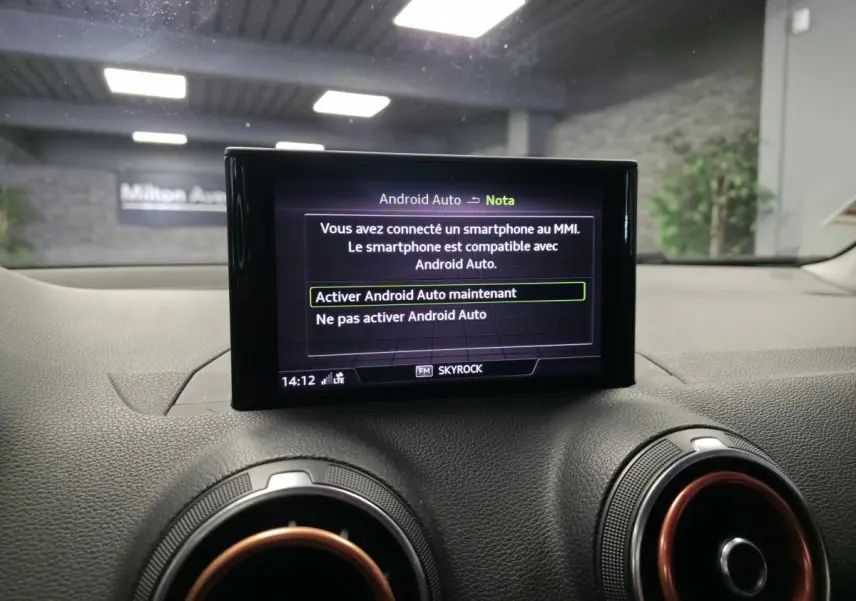 Écran central du système MMI affichant l'activation d'Android Auto, avec aérateurs ronds à décor rouge dans un Audi Q2 noir.