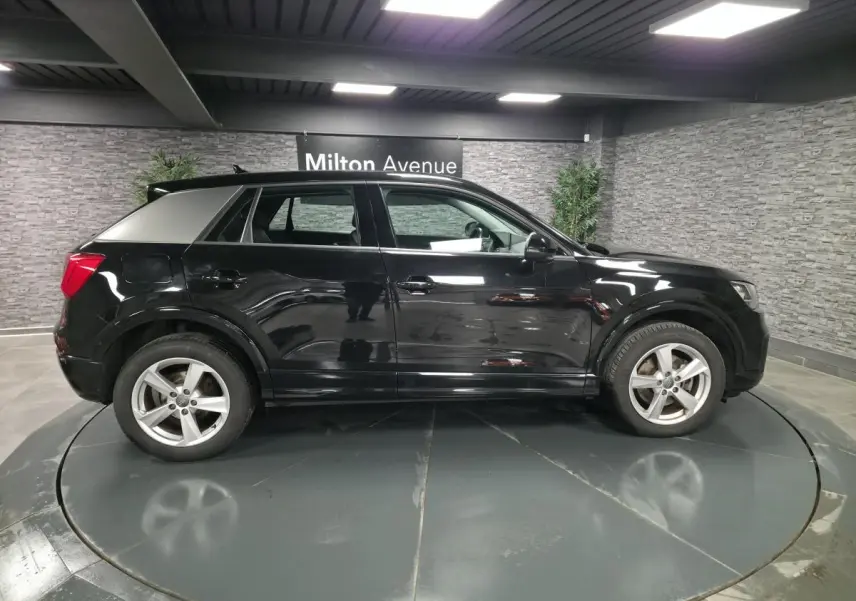 Audi Q2 noir vue de profil côté gauche dans un showroom avec jantes 5 branches et toit noir brillant.