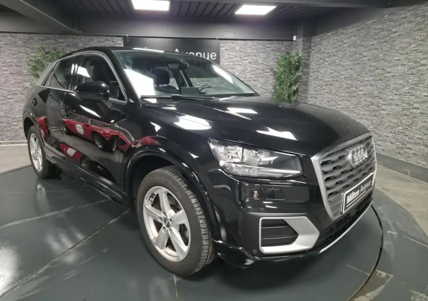 Audi Q2 noire vue en 3/4 avant droit, avec calandre grise et jantes aluminium 5 branches en étoile.