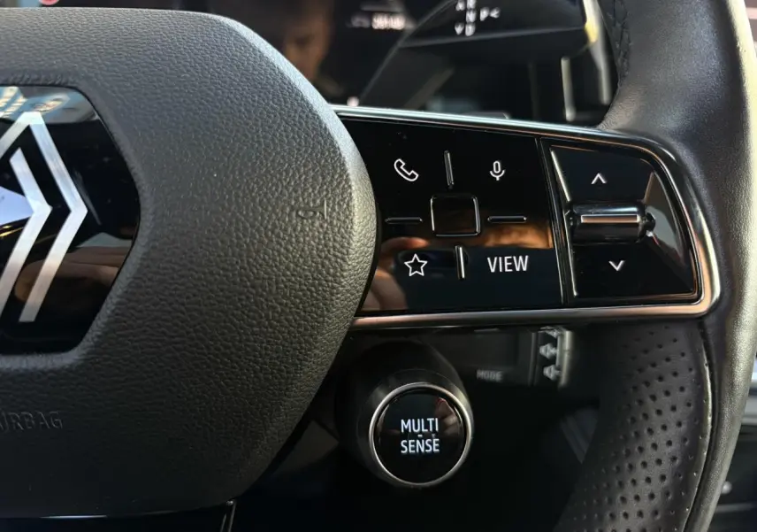 Gros plan sur le volant cuir noir perforé du Renault Austral 2023 avec commandes multifonctions et bouton Multi Sense.