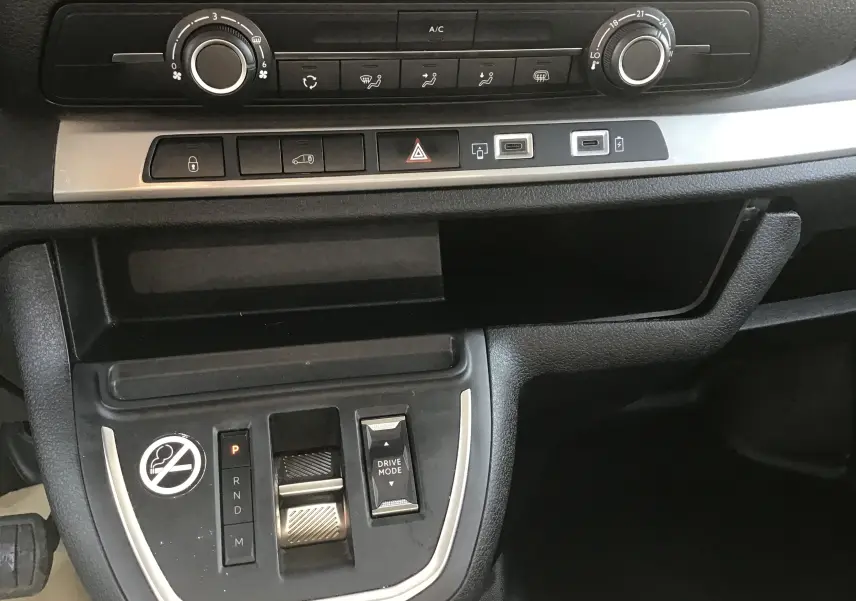 Vue rapprochée du tableau de bord et console centrale noire du Fiat Scudo Fourgon blanc, avec commandes climatisation et boîte auto.