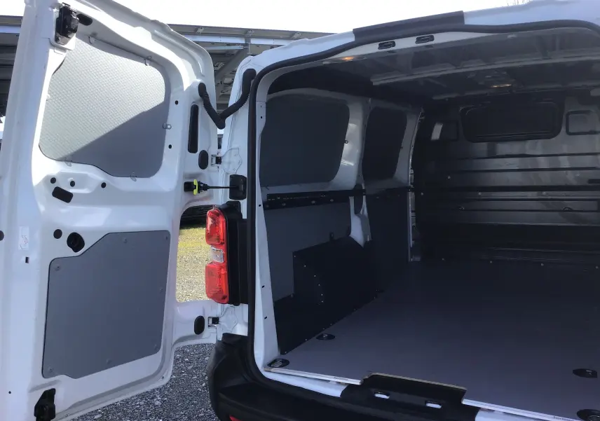 Vue arrière ouverte du FIAT Scudo Fourgon blanc 2024, montrant l’intérieur spacieux et protégé du coffre avec panneaux gris.