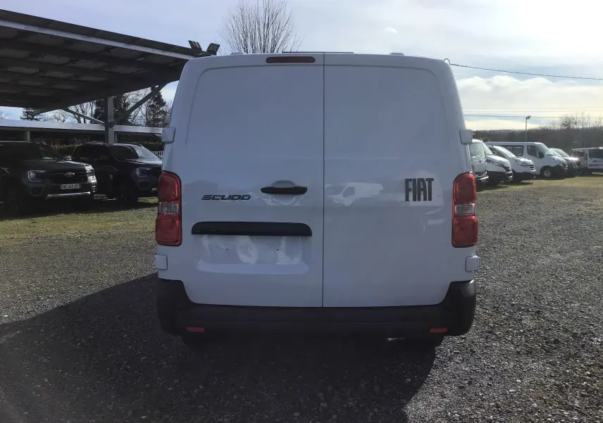 Vue arrière d'un FIAT Scudo Fourgon blanc 2024 avec portes battantes et feux arrière rouges, stationné en extérieur.