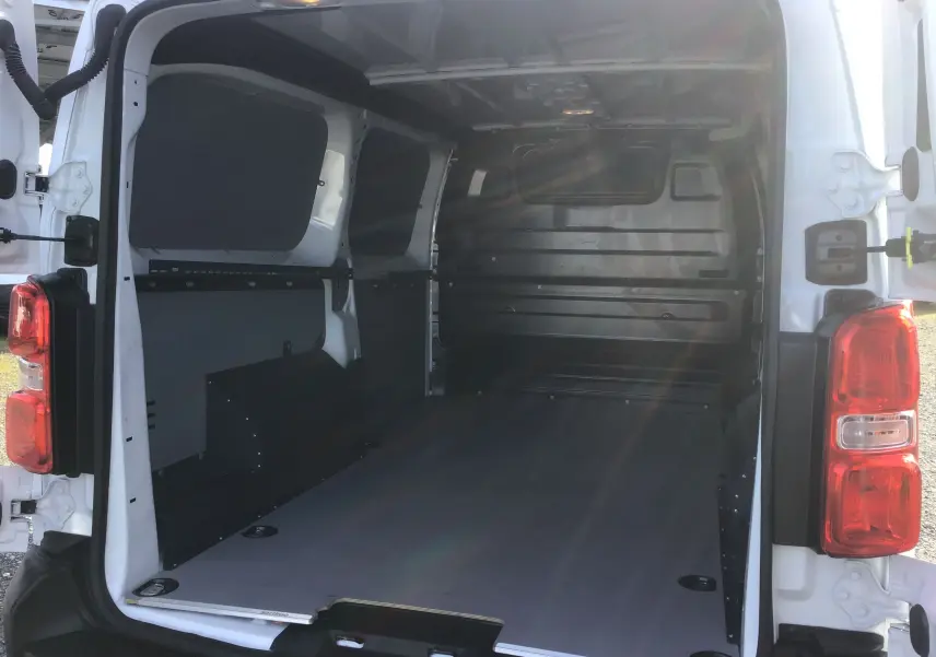 Vue arrière ouverte du FIAT Scudo Fourgon blanc 2024, montrant l’espace de chargement vide avec protections intérieures noires.