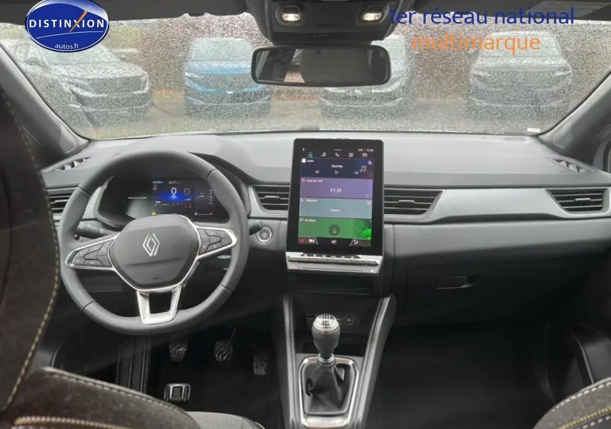 Vue intérieure avant du Renault Captur gris rafale 2025, volant multifonction et écran tactile central vertical.