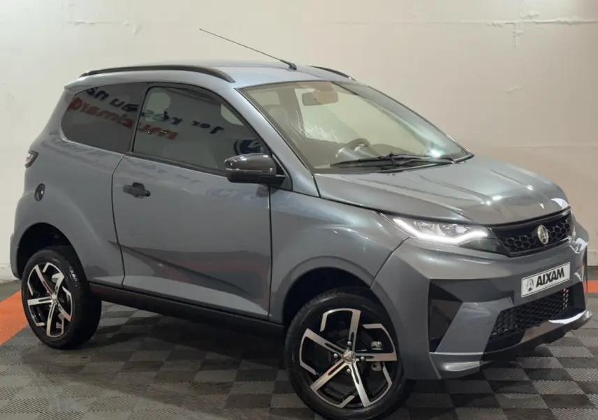 Vue 3/4 avant d'une Aixam Ambition 0.5 Crossover Premium gris foncé avec jantes noires et rétroviseur caméra côté gauche.