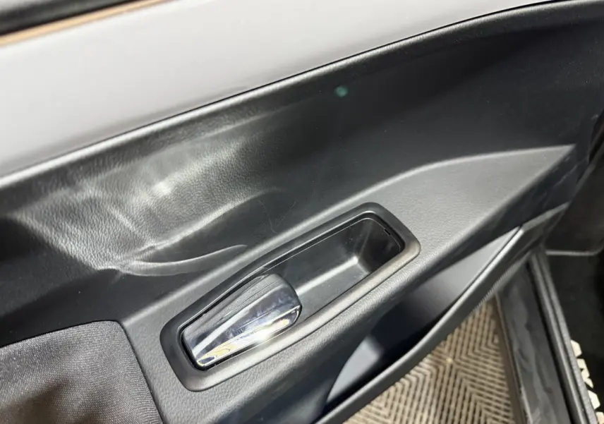 Détail de la poignée de porte intérieure noire de l'AIXAM AMBITION 0.5 CROSSOVER PREMIUM 2026, côté conducteur.