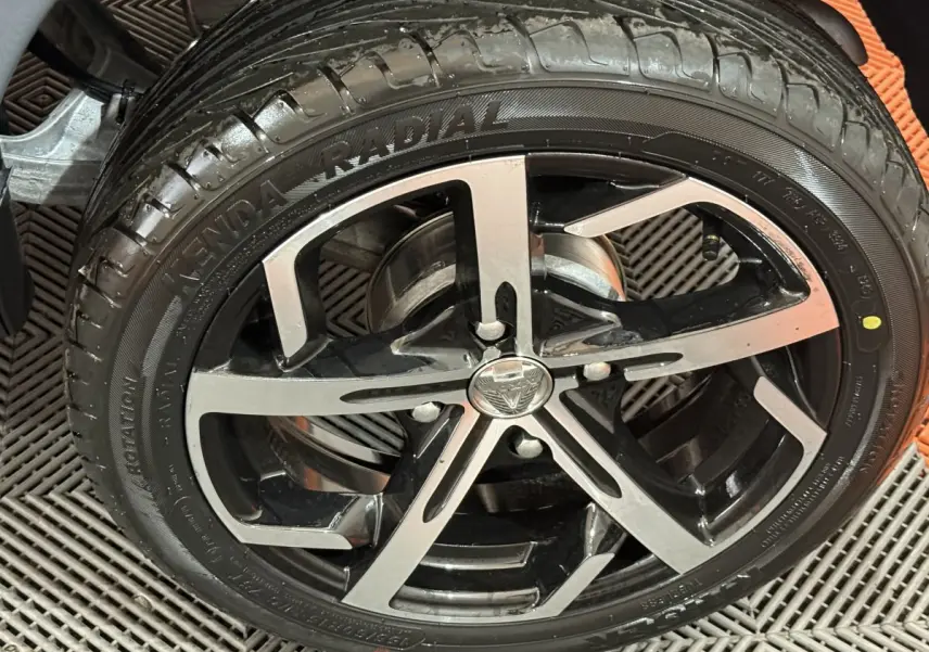 Gros plan sur la jante noire et argentée d’une Aixam Ambition 0.5 Crossover Premium gris foncé, vue côté roue.