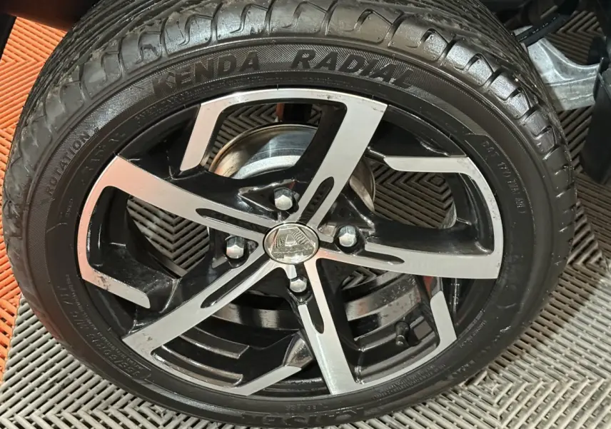 Gros plan sur la roue avant droite de l'AIXAM AMBITION 0.5 CROSSOVER PREMIUM gris foncé avec jante noire et argent.