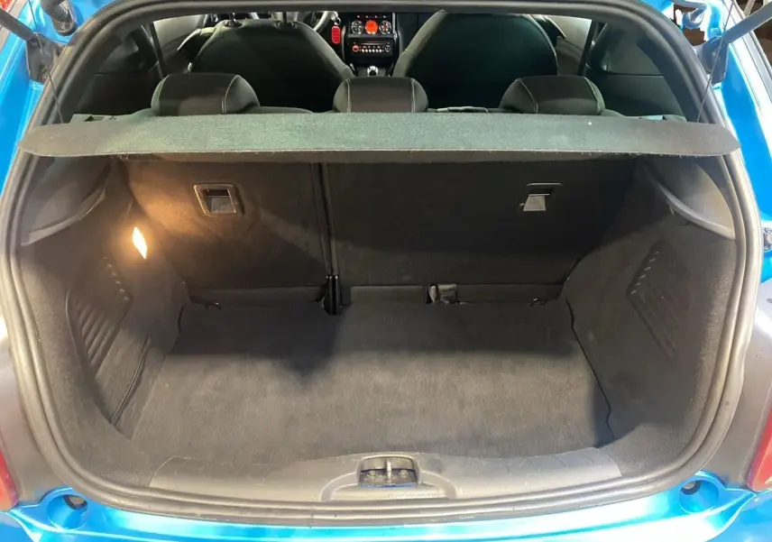 Coffre ouvert vu de l’arrière d’une Citroën DS3 bleu avec toit blanc, montrant l’espace de chargement vide.