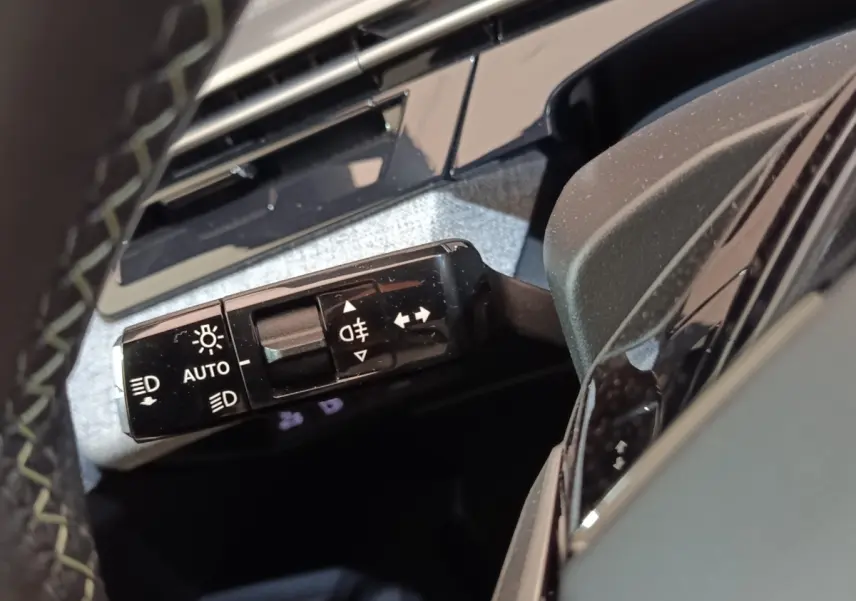 Gros plan sur la commande des phares et clignotants du Peugeot 5008 gris clair, intérieur côté gauche.