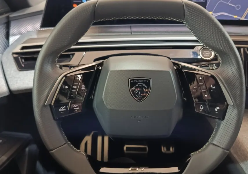 Volant cuir noir de Peugeot 5008 1.6 PHEV GT 2026 vu de face avec commandes multifonctions et bouton démarrage.