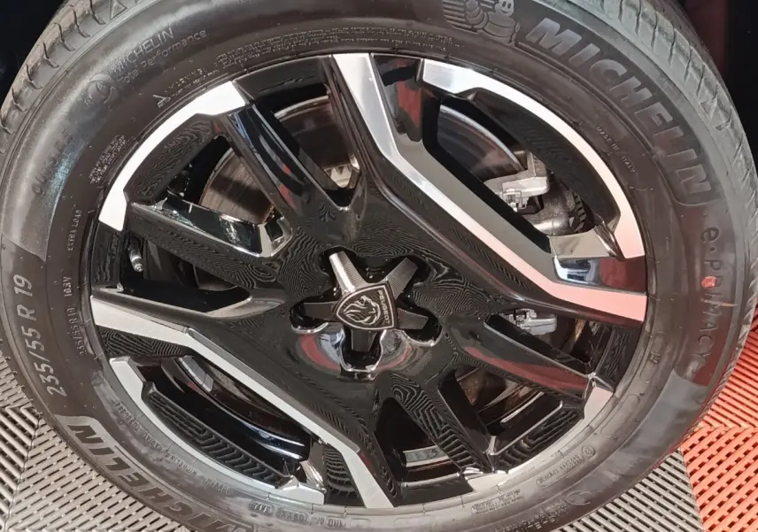 Gros plan sur la jante noire et argentée de 19 pouces du Peugeot 5008 gris clair, pneu Michelin visible.