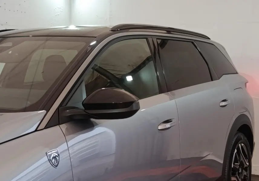 Vue latérale droite du Peugeot 5008 gris clair 2026 avec logo lion et vitres teintées.