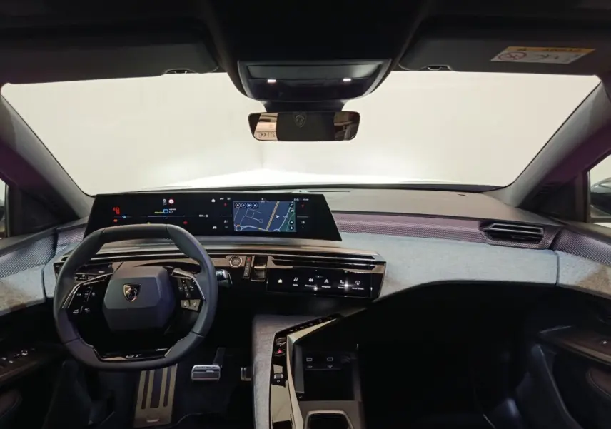Vue intérieure avant du Peugeot 5008 gris clair 2026, tableau de bord numérique large et volant cuir multifonctions.