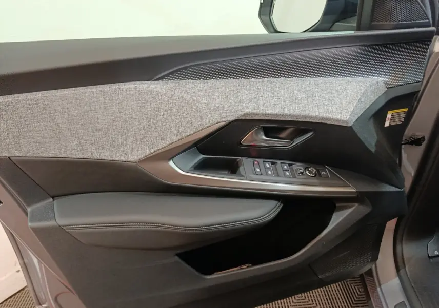 Vue intérieure côté gauche de la porte avant gris clair du Peugeot 5008 avec commandes électriques et habillage tissu et cuir.