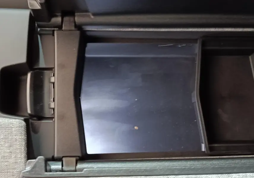 Vue rapprochée de la console centrale ouverte du Peugeot 5008 gris clair, montrant un compartiment de rangement intérieur.