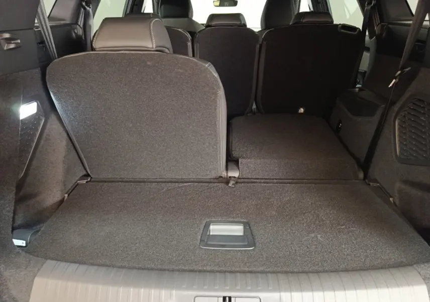 Vue arrière intérieure du coffre du Peugeot 5008 gris clair avec sièges rabattus partiellement à droite.