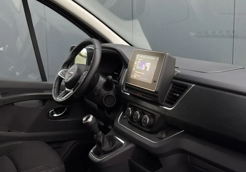 Intérieur côté conducteur du Nissan Primastar Combi 2025 noir, avec tableau de bord moderne et écran tactile central.
