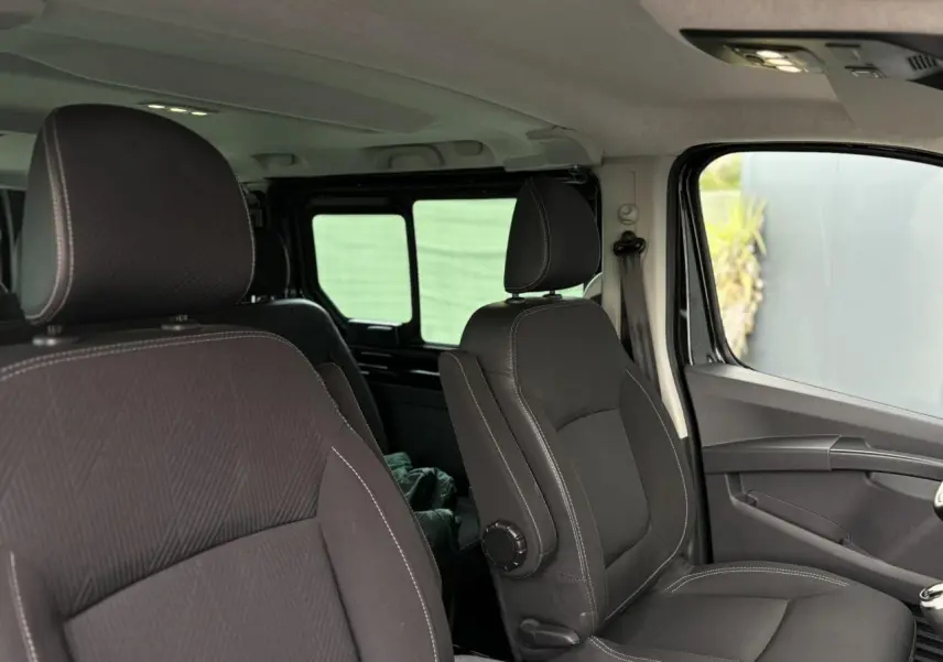 Intérieur du Nissan Primastar Combi 2025, vue côté droit sur les sièges avant noirs avec surpiqûres blanches.