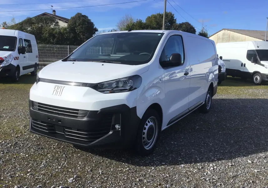 Vue 3/4 avant droite d’un FIAT Scudo Fourgon blanc 2024 avec pare-chocs noir et jantes acier, stationné sur gravier.