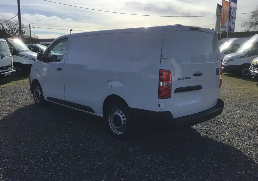 Vue 3/4 arrière droite d’un FIAT Scudo Fourgon blanc 2024 avec garde au sol réhaussée et protections noires.
