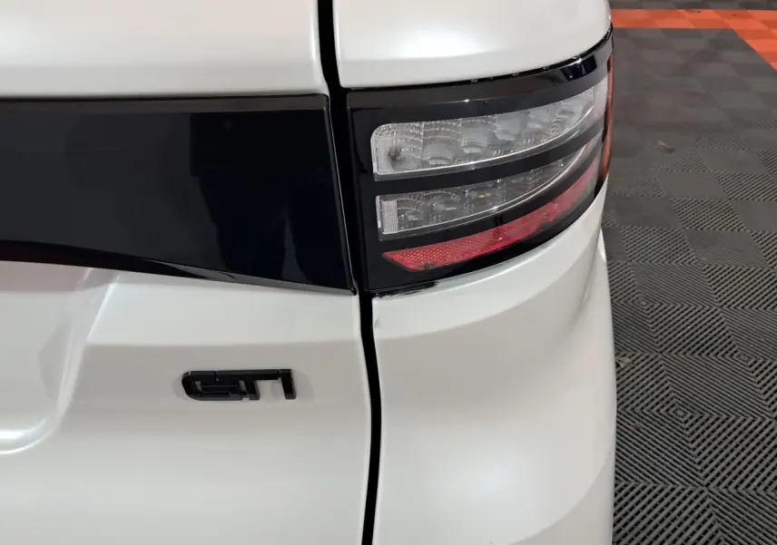 Gros plan sur le feu arrière droit blanc d'une Aixam Ambition 0.5 City Coupe GTI avec logo GTI noir.