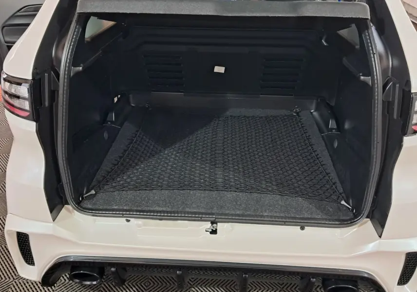 Vue arrière du coffre ouvert de l'AIXAM AMBITION 0.5 CITY COUPE GTI blanc, avec filet de rangement et détails noirs.