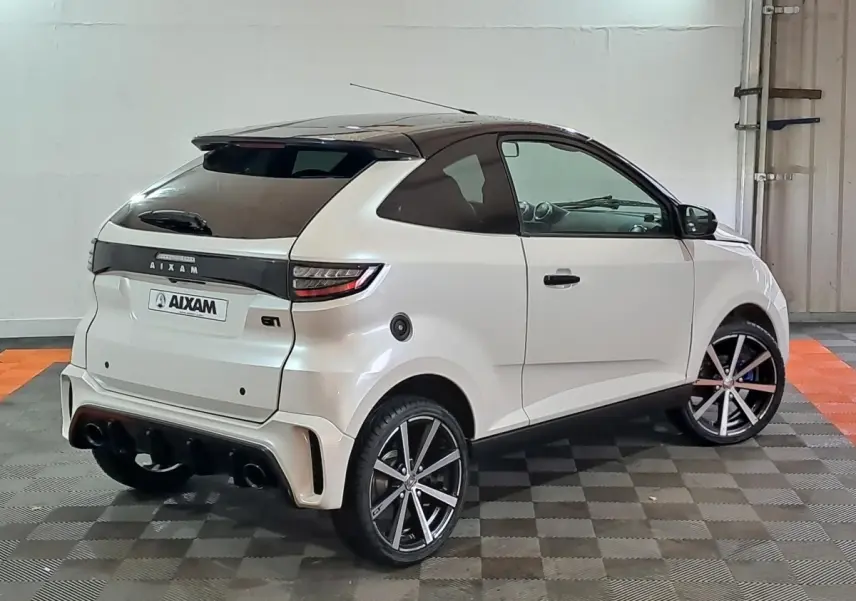 Vue 3/4 arrière droite d'une AIXAM Ambition 0.5 City Coupe GTI blanche avec jantes noires et toit noir.