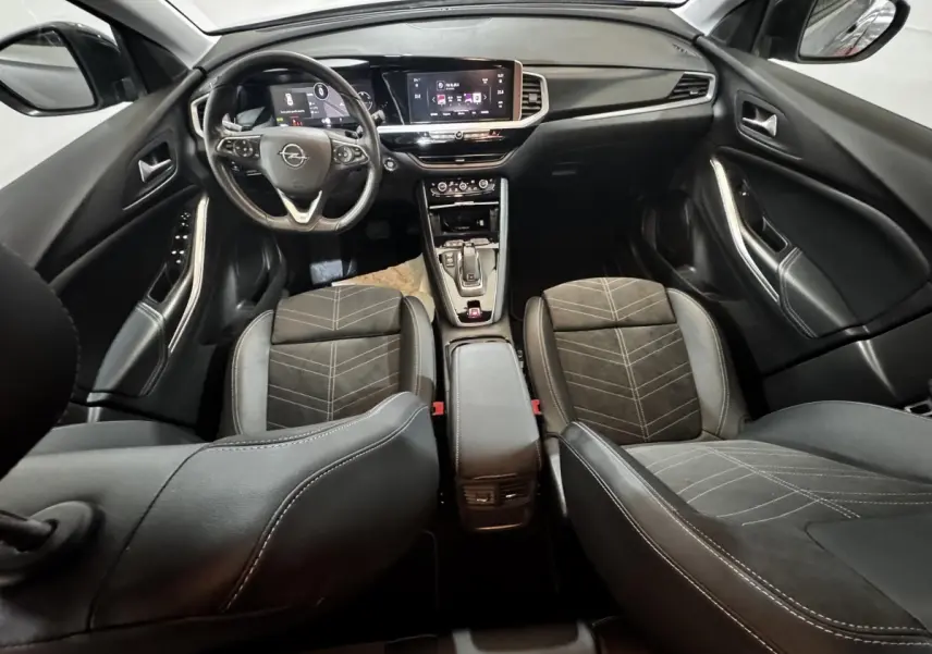 Vue intérieure avant de l’Opel Grandland 2022, sièges noirs, volant cuir multifonctions et écran tactile central.