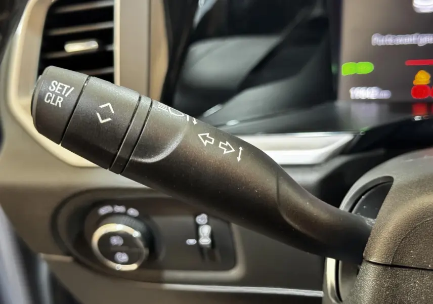 Gros plan sur la manette de clignotant et commandes au volant d'un Opel Grandland gris clair, intérieur moderne.