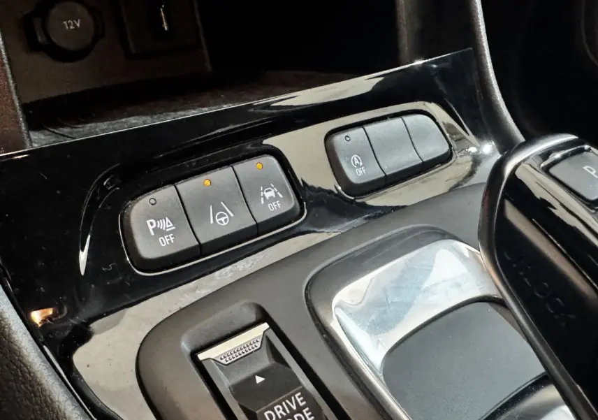 Gros plan sur la console centrale noire avec boutons d’aide à la conduite et levier de vitesse automatique.