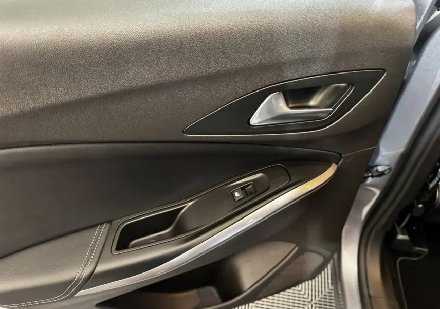 Gros plan sur la porte intérieure côté conducteur d’un Opel Grandland gris clair, avec poignée argentée et bouton de verrouillage.