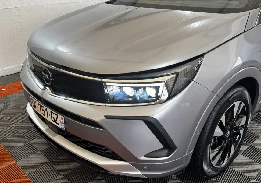 Vue 3/4 avant droit d'un Opel Grandland gris clair avec phares LED et jantes alliage noires.