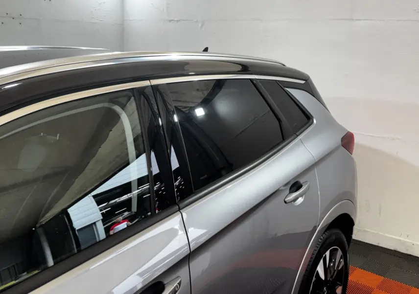 Vue latérale droite d’un Opel Grandland gris clair avec toit noir et jantes noires en intérieur.