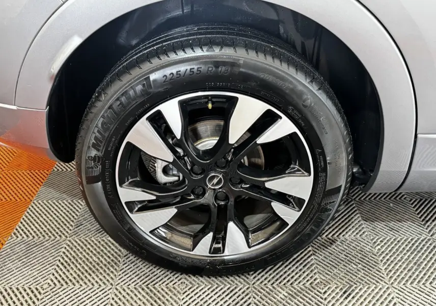 Gros plan sur la roue avant droite d’un Opel Grandland gris clair, jante alliage bicolore et pneu Michelin.
