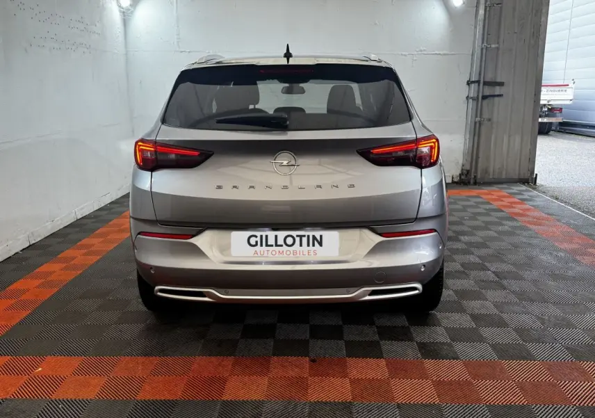Vue arrière d’un Opel Grandland gris clair 2022 avec feux LED allumés dans un garage.