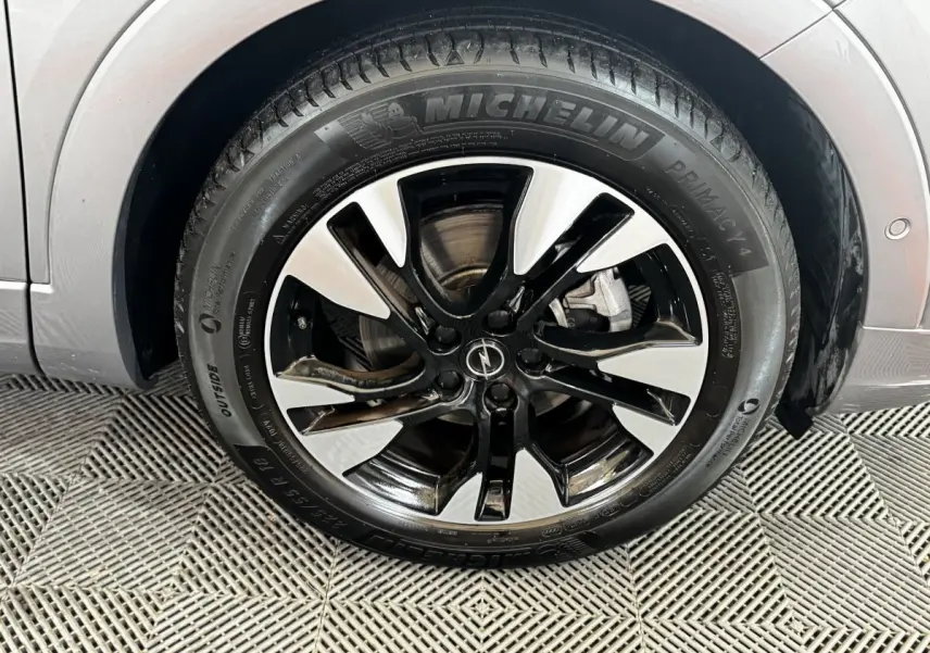 Gros plan sur la roue avant droite gris clair d’un Opel Grandland 2022 avec jante alliage noir et argent.