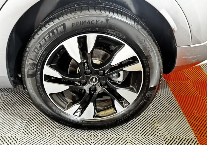 Gros plan sur la roue avant droite d’un Opel Grandland gris clair avec jante alliage bicolore et pneu Michelin.