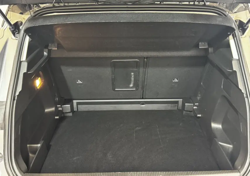Coffre ouvert vu de l'arrière d'un Opel Grandland gris clair, montrant l'espace de chargement et banquette rabattable.