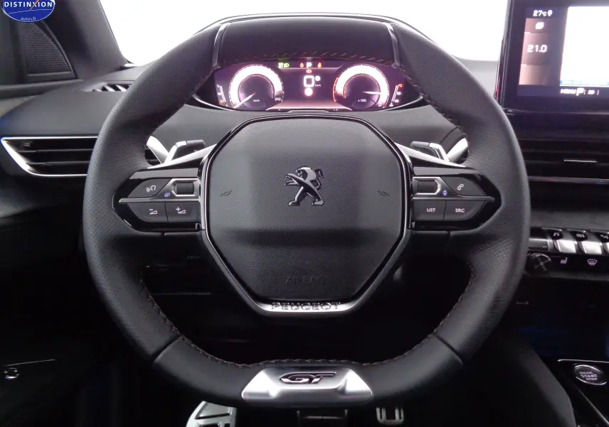 Vue rapprochée du volant GT noir perforé du Peugeot 3008 2023 avec tableau de bord numérique et écran tactile.