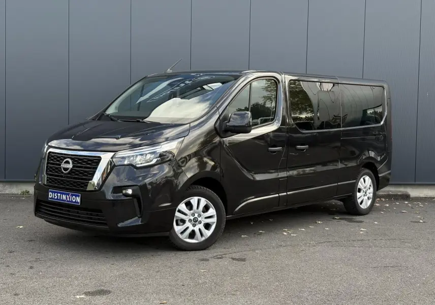 Nissan Primastar Combi noir métal en 3/4 avant droit, avec hayon vitré et vitres arrière surteintées.