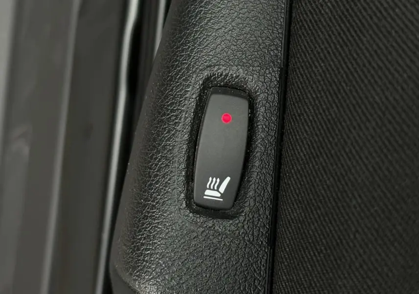 Bouton allumé de siège chauffant sur panneau intérieur noir du Nissan Primastar Combi L2 2025.
