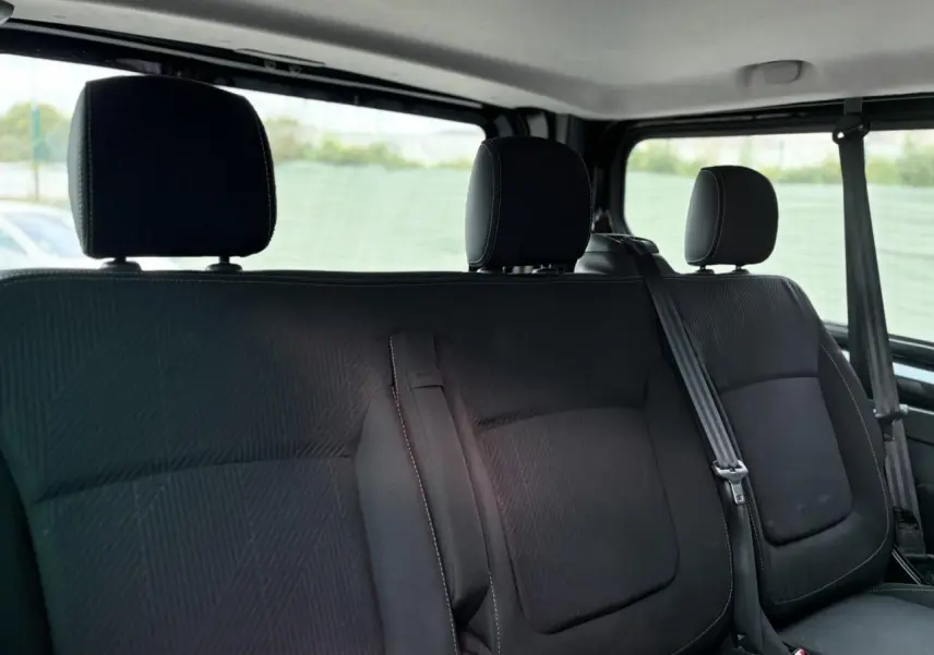 Vue rapprochée sur la banquette arrière noire du Nissan Primastar Combi 2025 avec appuie-têtes et ceintures visibles.