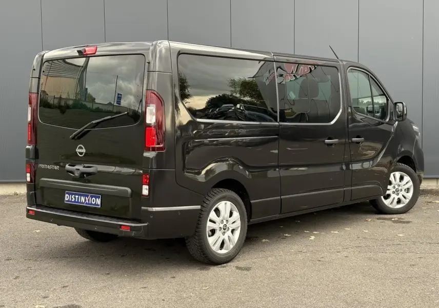 Vue 3/4 arrière droite d'un Nissan Primastar Combi noir métal avec hayon vitré et vitres latérales teintées.